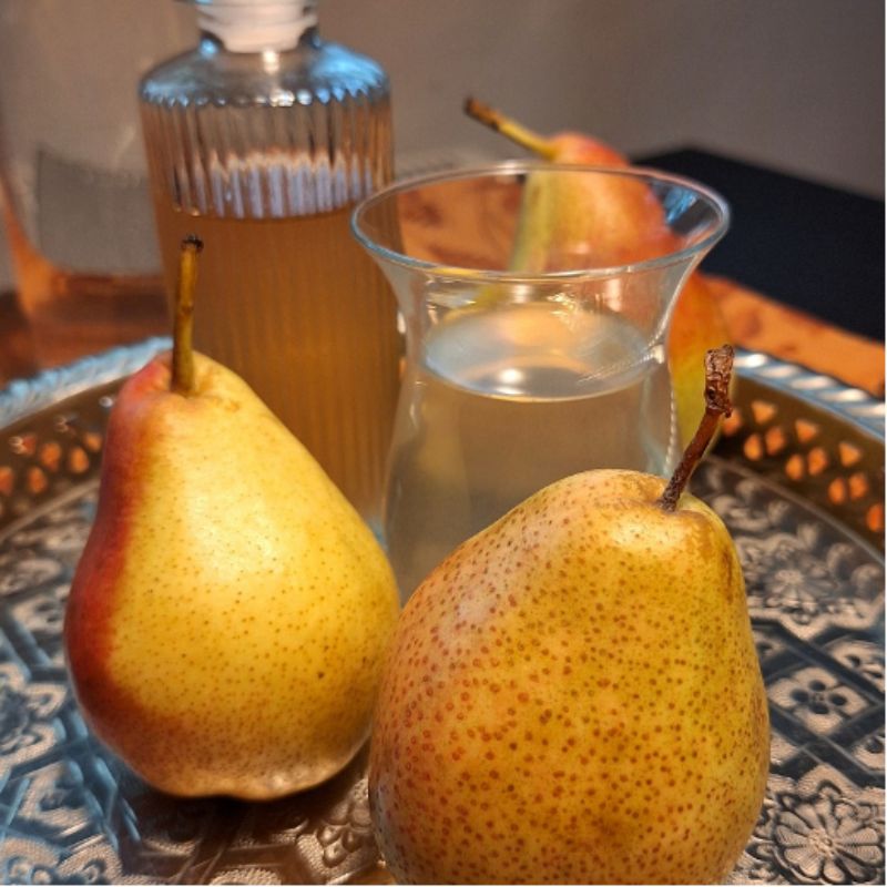 : Birnen-Shrub, ein essigsaurer Sirup, hier schmale Glasflasche mit Birnen-Shrub, im Tulpenglas mit Wasser verdünnter Shrub, vorne zwei goldgelbe Birnen auf marokkanischem Tablett Fotocredit: Liudmyla Honcharova, Pexels  @Dalslandliebe